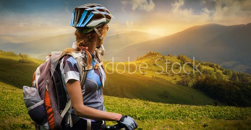 Young woman with bicycle standing in the mountains 
