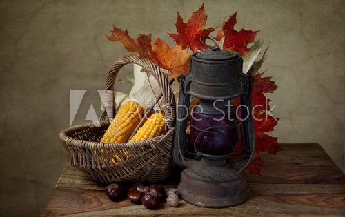 Herbstliches Stilleben mit Petroleumlampe und Mais in Weidenkorb