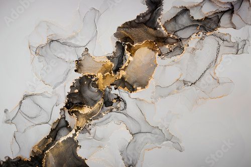 Abstract fluid art painting background in alcohol ink technique, mixture of black and gray paints with glowing golden veins. Transparent overlayers of ink create lines and gradients.