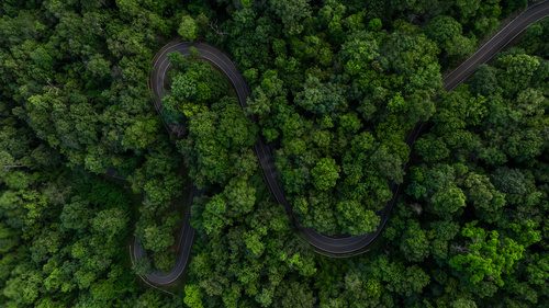 Aerial view asphalt road on green forest, Curve asphalt road on mountain green forest, Countryside road passing green forrest and mountain.