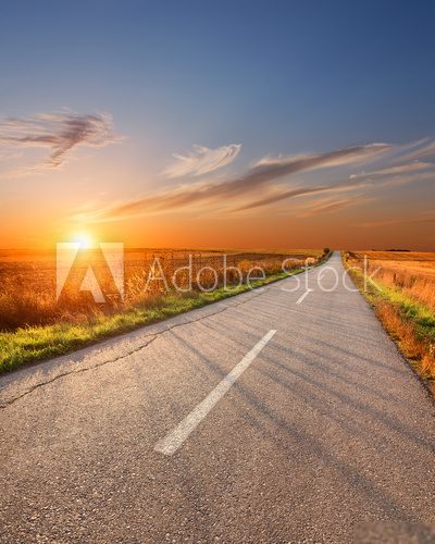 Driving on an empty aspalt road at sunset