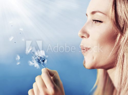 Happy beautiful girl blowing dandelion 