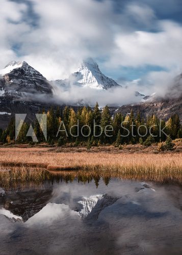 Mount Assiniboine with autumn forest reflection on Lake Magog at provincial park