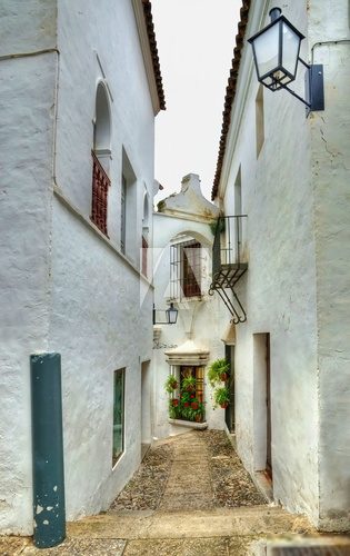 Small narrow street in spanish city with white houses