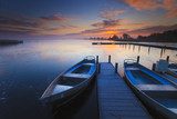 Peaceful sunrise with dramatic sky and boats and a jetty