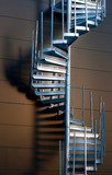 Metal spiral staircase casting shadow on wall in evening light 