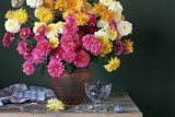 Still life with pink and yellow chrysanthemums in a clay jug and